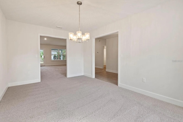 carpeted empty room with a chandelier