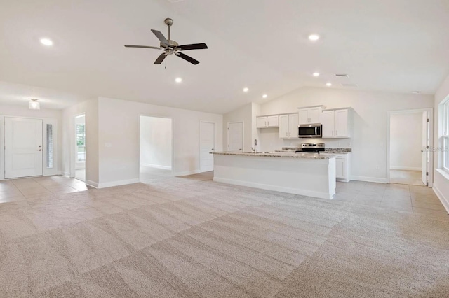 unfurnished living room with light colored carpet, ceiling fan, lofted ceiling, and sink