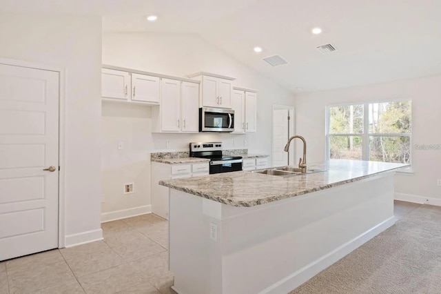 kitchen with appliances with stainless steel finishes, sink, a center island with sink, white cabinetry, and lofted ceiling