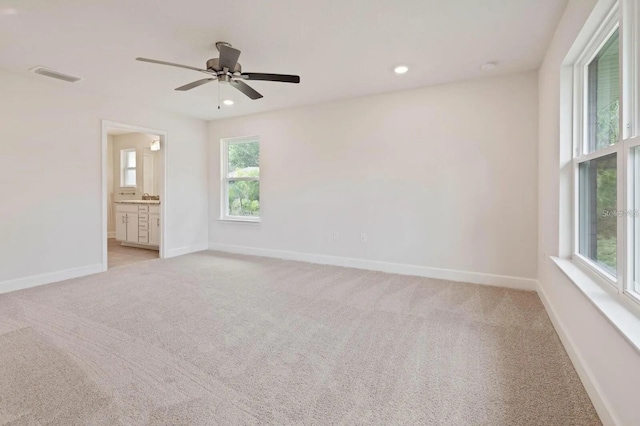 unfurnished room featuring ceiling fan, light carpet, and a wealth of natural light