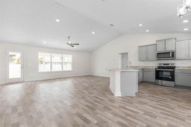 kitchen with light wood-type flooring, stainless steel appliances, gray cabinets, and lofted ceiling