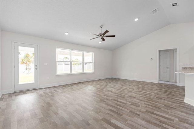 unfurnished living room featuring ceiling fan, light wood-type flooring, a wealth of natural light, and vaulted ceiling