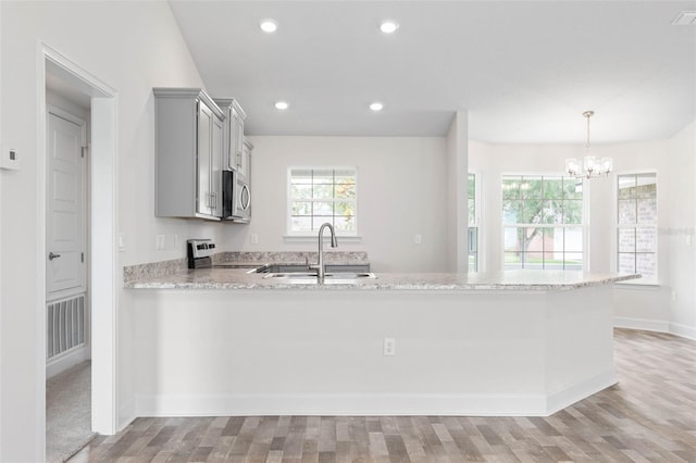 kitchen with sink, kitchen peninsula, light hardwood / wood-style floors, gray cabinets, and range