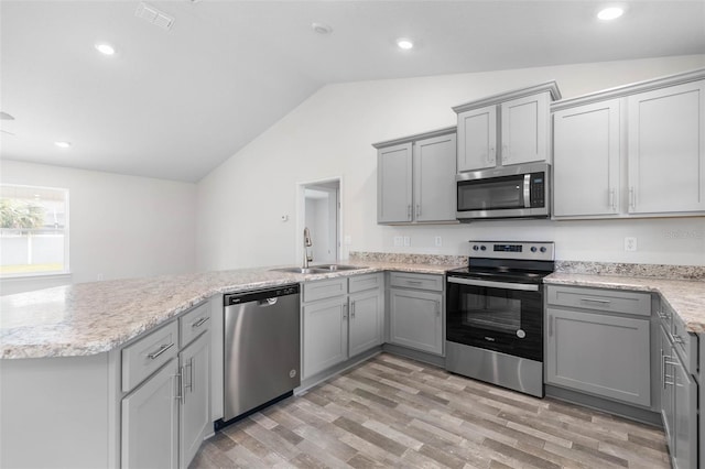 kitchen with sink, light hardwood / wood-style floors, vaulted ceiling, and appliances with stainless steel finishes