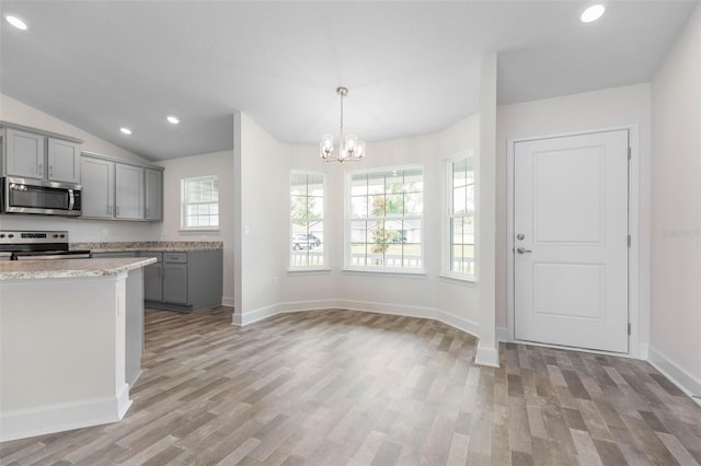 kitchen with gray cabinetry, light hardwood / wood-style floors, stainless steel appliances, and a chandelier