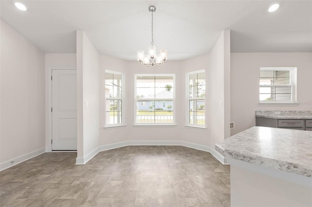 unfurnished dining area featuring a wealth of natural light, recessed lighting, an inviting chandelier, and baseboards