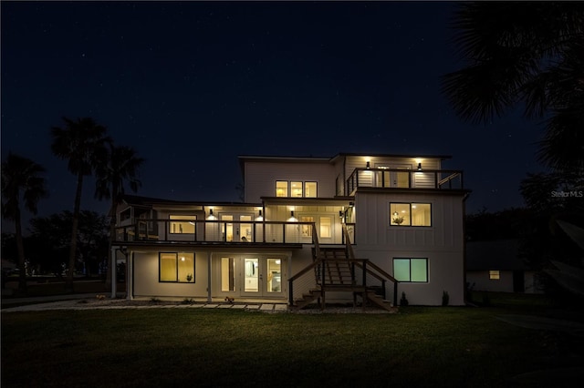 back house at twilight with a lawn and a balcony