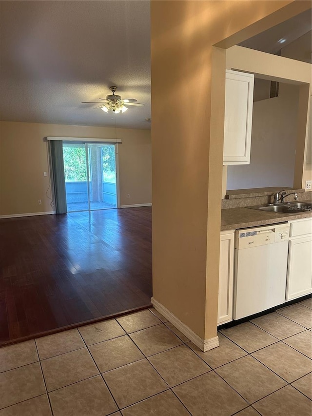 kitchen featuring white dishwasher, white cabinets, light tile patterned floors, and sink