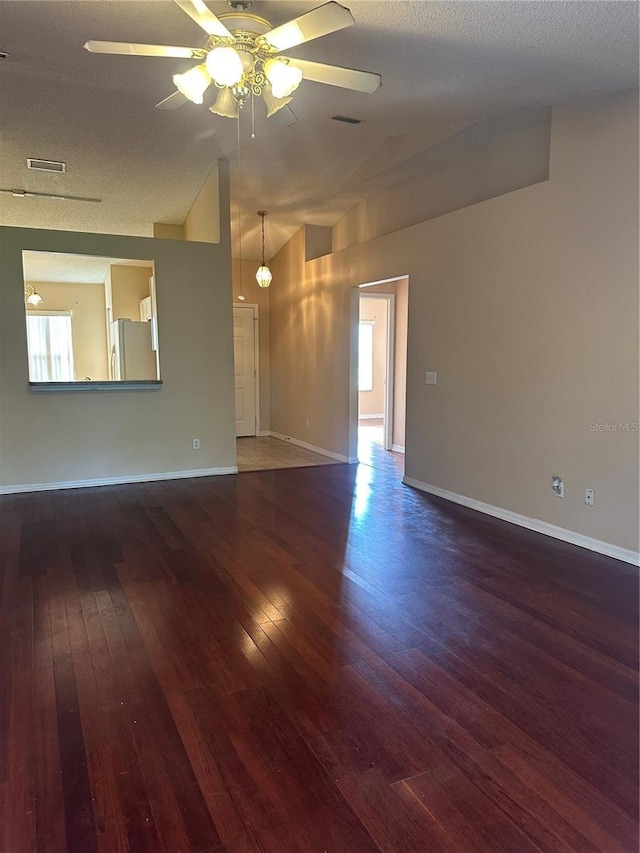 spare room featuring a textured ceiling, ceiling fan, dark hardwood / wood-style floors, and vaulted ceiling