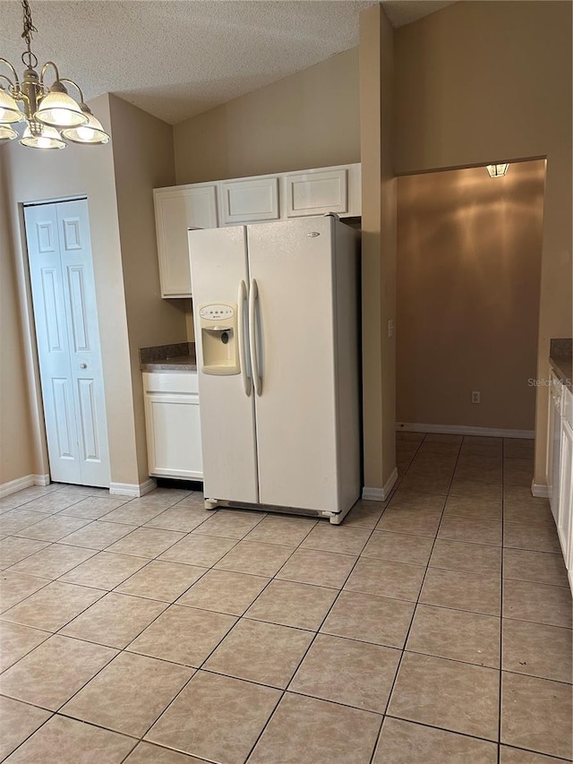 kitchen featuring white cabinetry, white fridge with ice dispenser, hanging light fixtures, and an inviting chandelier