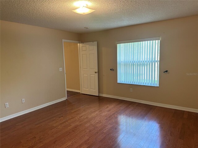 spare room with a textured ceiling and dark hardwood / wood-style flooring