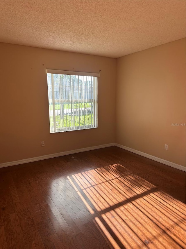 empty room with a textured ceiling and hardwood / wood-style flooring