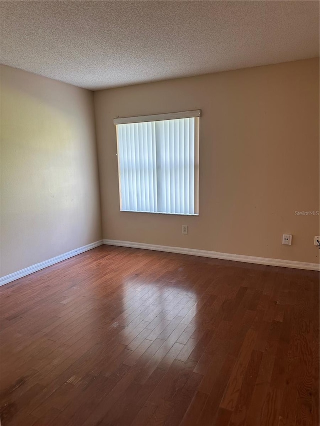 spare room with a textured ceiling and dark wood-type flooring