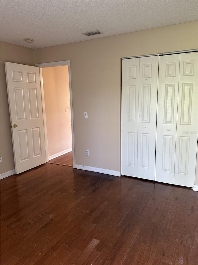 unfurnished bedroom with dark hardwood / wood-style flooring, a closet, and a textured ceiling