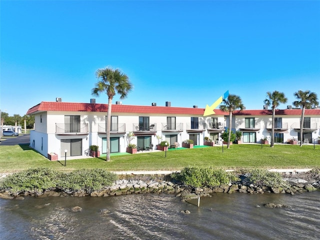 back of house featuring a lawn and a water view