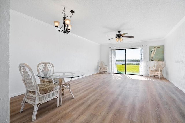 dining area with wood-type flooring, ceiling fan with notable chandelier, and ornamental molding