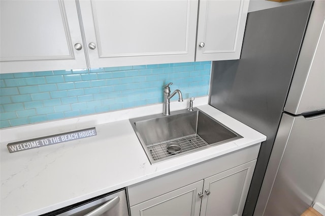 kitchen featuring decorative backsplash, stainless steel appliances, white cabinetry, and sink