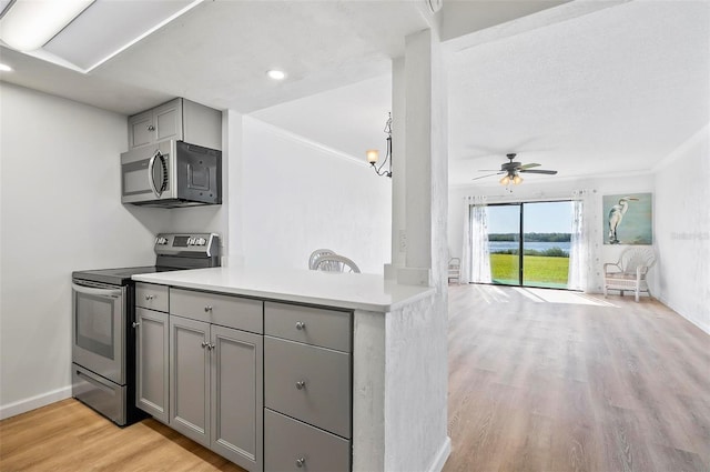 kitchen featuring crown molding, ceiling fan, gray cabinets, light wood-type flooring, and appliances with stainless steel finishes