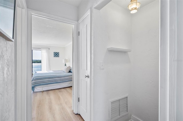 hallway with light wood-type flooring and a textured ceiling