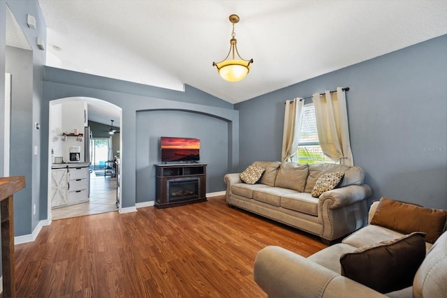 living room with hardwood / wood-style floors, ceiling fan, lofted ceiling, and a fireplace