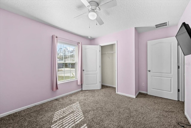 unfurnished bedroom with carpet, a textured ceiling, ceiling fan, and a closet