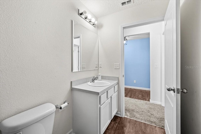 bathroom featuring vanity, hardwood / wood-style flooring, toilet, and a textured ceiling