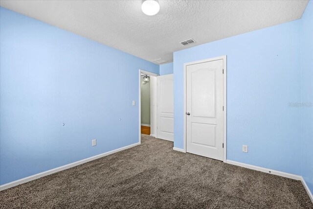 unfurnished bedroom with a textured ceiling and carpet