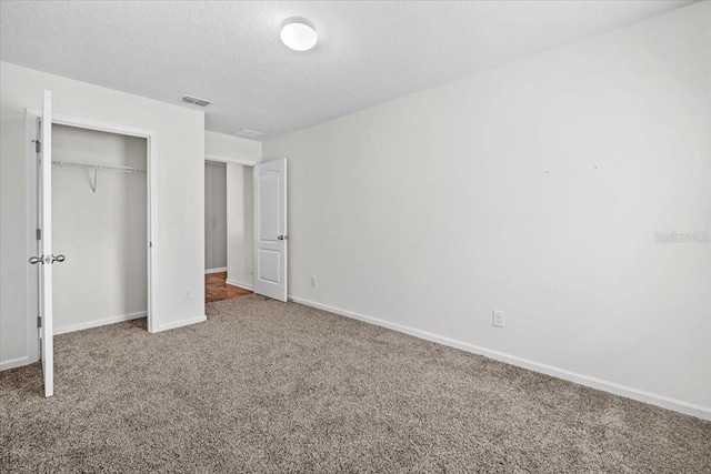 unfurnished bedroom with carpet flooring, a textured ceiling, and a closet