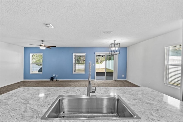 kitchen with plenty of natural light, decorative light fixtures, sink, and a textured ceiling