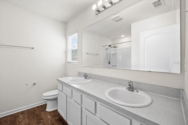 bathroom with hardwood / wood-style floors, vanity, a textured ceiling, toilet, and walk in shower