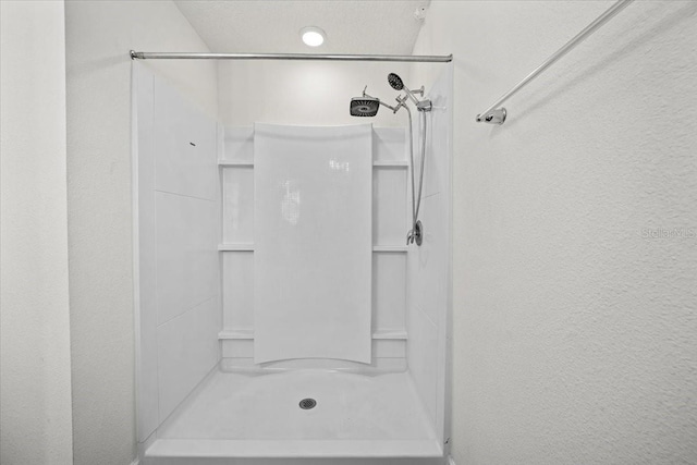 bathroom with walk in shower and a textured ceiling