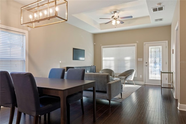 dining room with a raised ceiling, ceiling fan, and dark wood-type flooring