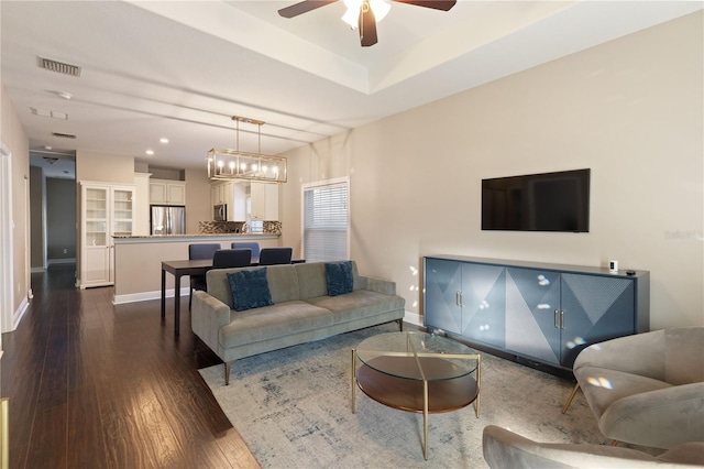 living room with ceiling fan with notable chandelier and dark hardwood / wood-style flooring