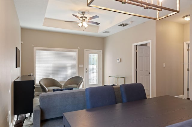 dining space with a raised ceiling and ceiling fan