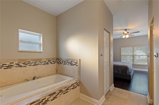 bathroom with tiled bath, ceiling fan, tile patterned flooring, and a healthy amount of sunlight