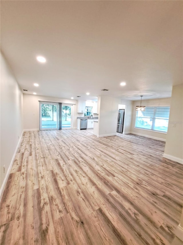 unfurnished living room with a healthy amount of sunlight and light hardwood / wood-style floors