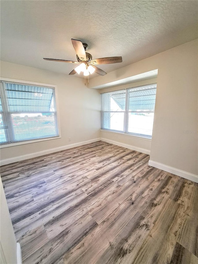 unfurnished room featuring ceiling fan, a healthy amount of sunlight, a textured ceiling, and hardwood / wood-style flooring