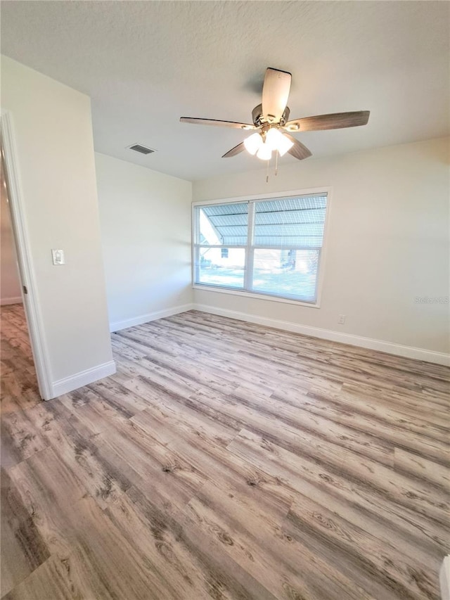 unfurnished room with a textured ceiling and light wood-type flooring