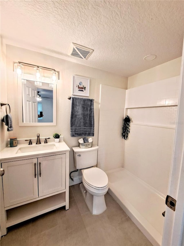 bathroom featuring a shower, a textured ceiling, vanity, and toilet