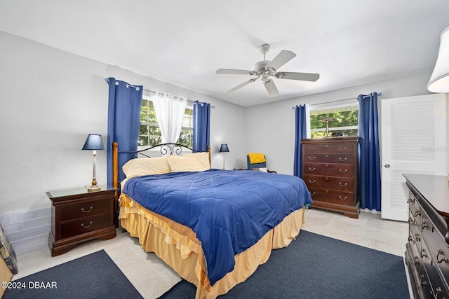 tiled bedroom featuring multiple windows and ceiling fan