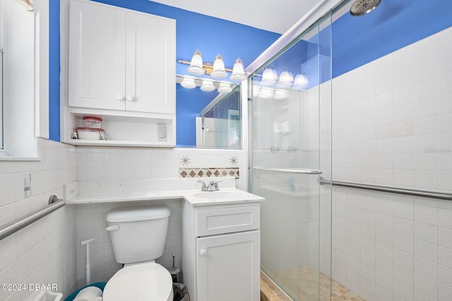 bathroom with vanity, toilet, a shower with shower door, and tile walls