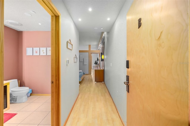 hallway featuring light hardwood / wood-style floors and a textured ceiling