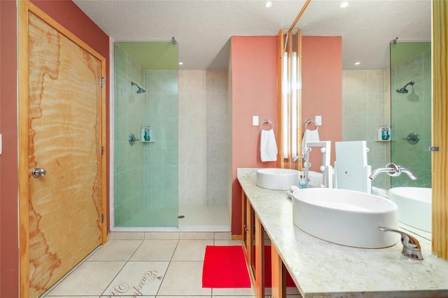 bathroom featuring tiled shower, vanity, tile patterned flooring, and a textured ceiling