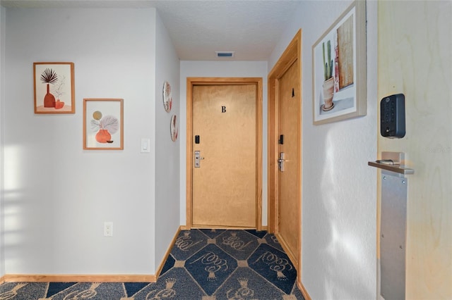 hall featuring a textured ceiling