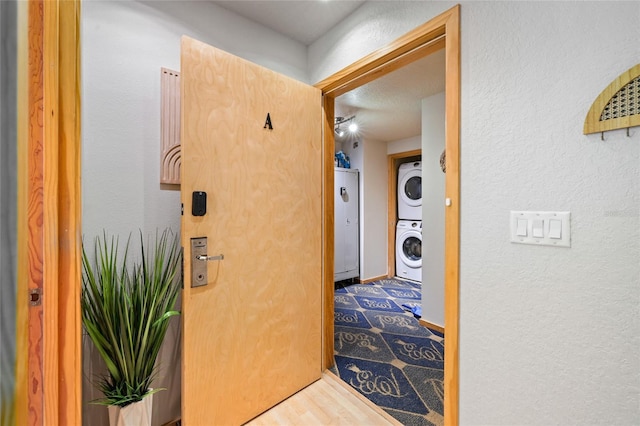 hallway with hardwood / wood-style flooring and stacked washer / drying machine