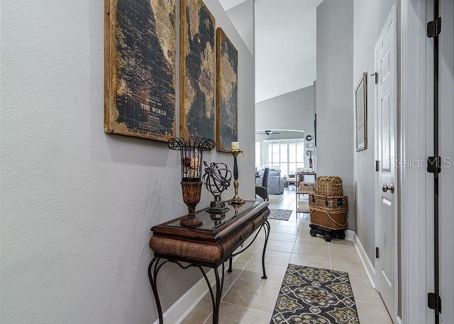 hall featuring light tile patterned floors and high vaulted ceiling