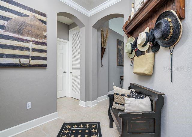 mudroom featuring light tile patterned floors and crown molding