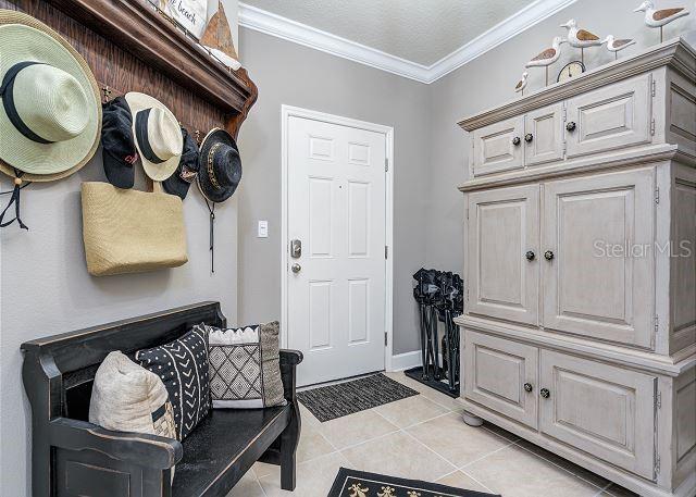 mudroom featuring light tile patterned flooring and ornamental molding