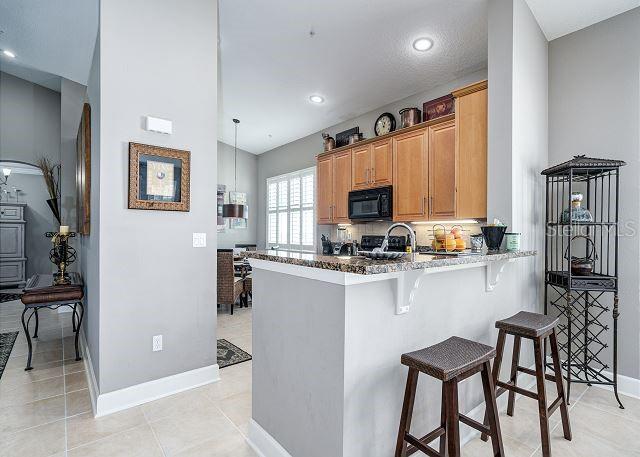 kitchen featuring stone counters, kitchen peninsula, decorative light fixtures, a kitchen bar, and decorative backsplash