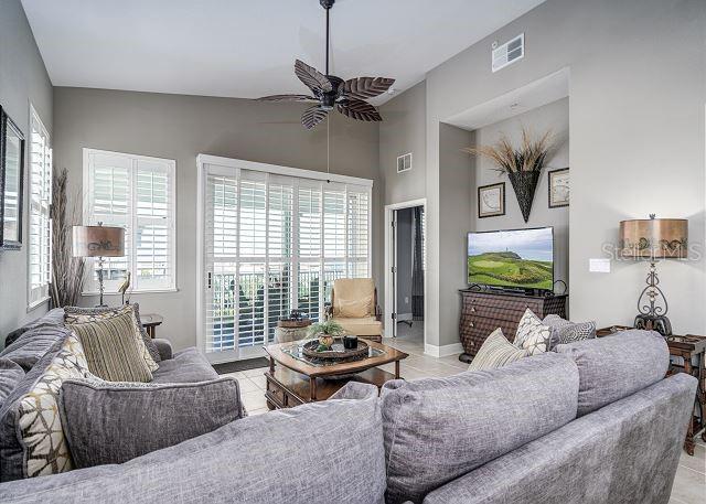 tiled living room with ceiling fan and vaulted ceiling